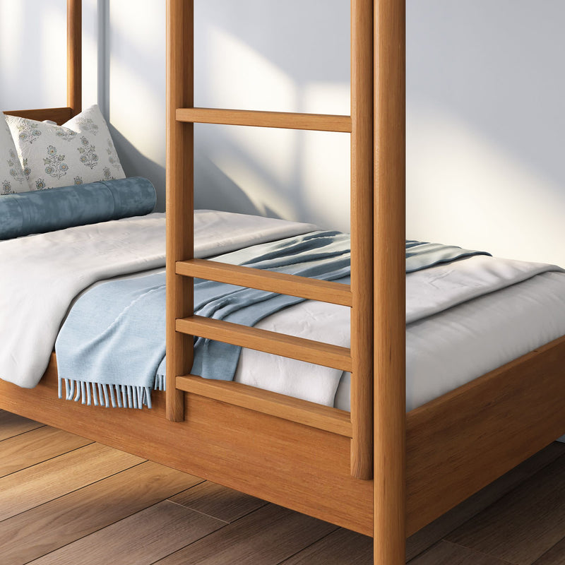 Minimalist wooden four-poster bed with white linens, light blue throw blanket and bolster pillow on hardwood floor