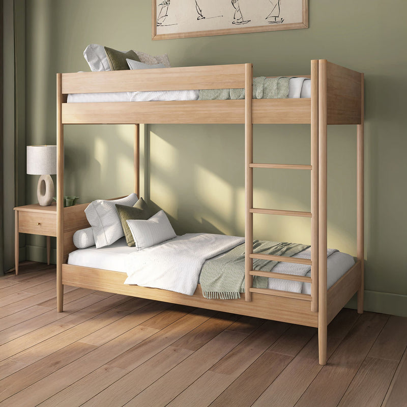 Modern light-wood bunk bed with ladder in a minimalist green bedroom, cozy white and sage bedding on hardwood floors beside a wooden nightstand and lamp — space-saving bedroom furniture.