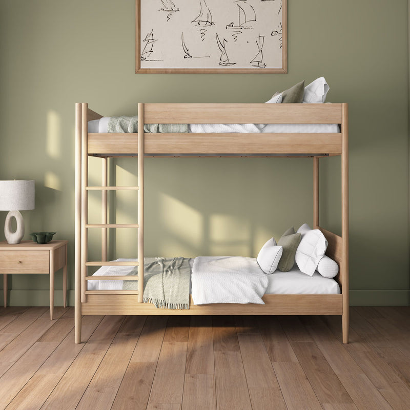 Wooden twin bunk bed with ladder in minimalist sage green bedroom, white bedding and bedside lamp