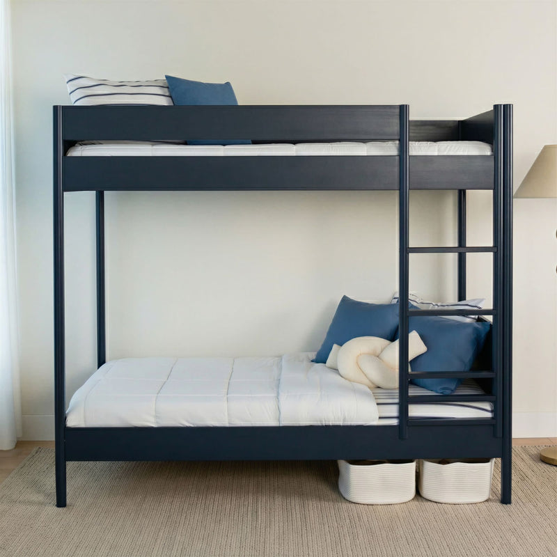 Navy blue twin-over-twin bunk bed with ladder, white bedding and blue pillows in a modern kids' bedroom with under-bed storage baskets and neutral decor