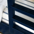 Close-up of navy blue metal bed frame with horizontal slats and white mattress, modern slatted headboard detail