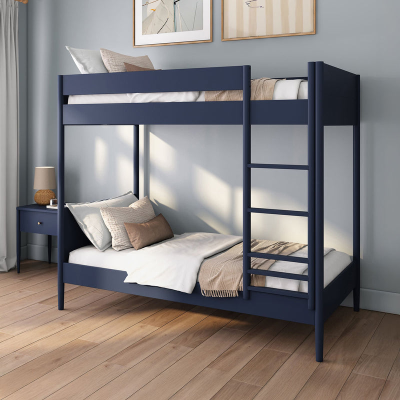 Navy blue twin-over-full bunk bed with ladder, cozy neutral bedding and pillows in modern kids' bedroom with wood floors and bedside table