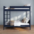 Modern navy blue two-tier bunk bed with ladder, white linens, beige throw and decorative pillows in a minimalist bedroom with hardwood floor