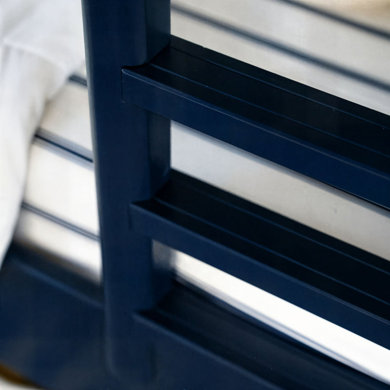 Close-up of navy metal bed frame slats with white mattress, modern industrial bedroom furniture