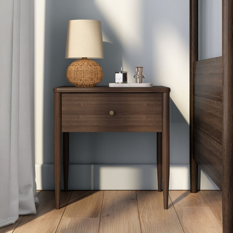 Mid-century modern walnut nightstand with wicker table lamp, scented candle and glass tray on hardwood bedroom floor