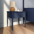 Modern navy blue bedside table nightstand with single drawer, rattan table lamp and candle tray on hardwood bedroom floor