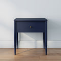 Navy blue modern bedside table with single drawer and brass knob on hardwood floor