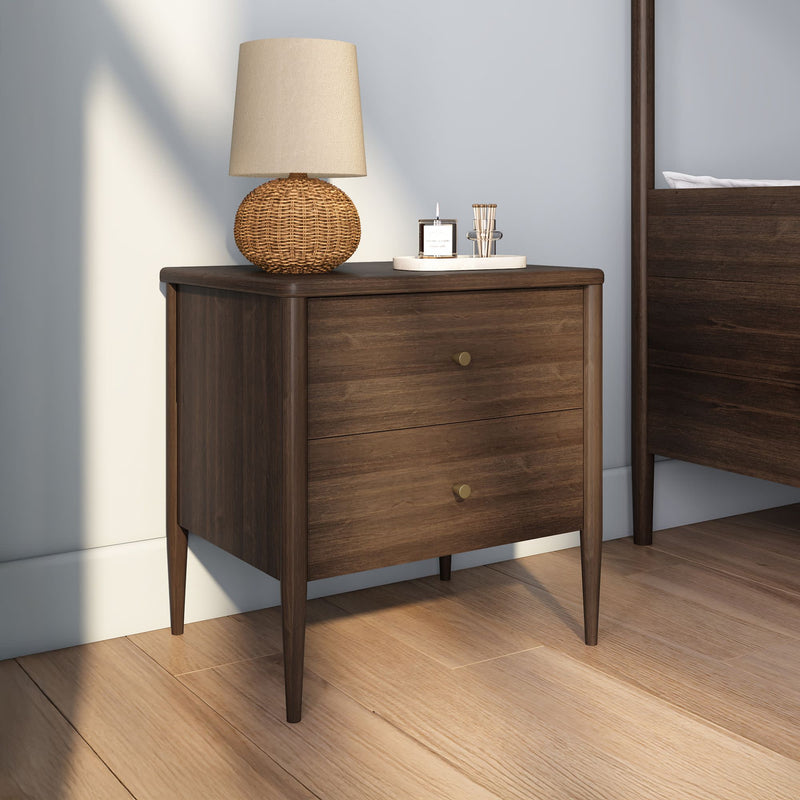 Mid-century modern walnut two-drawer nightstand with brass knobs, woven rattan table lamp and decorative tray with candle, styled bedroom interior on hardwood floor