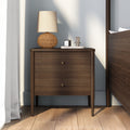 Walnut two-drawer nightstand with wicker table lamp, scented candle and reed diffuser on marble tray in modern bedroom with hardwood floors