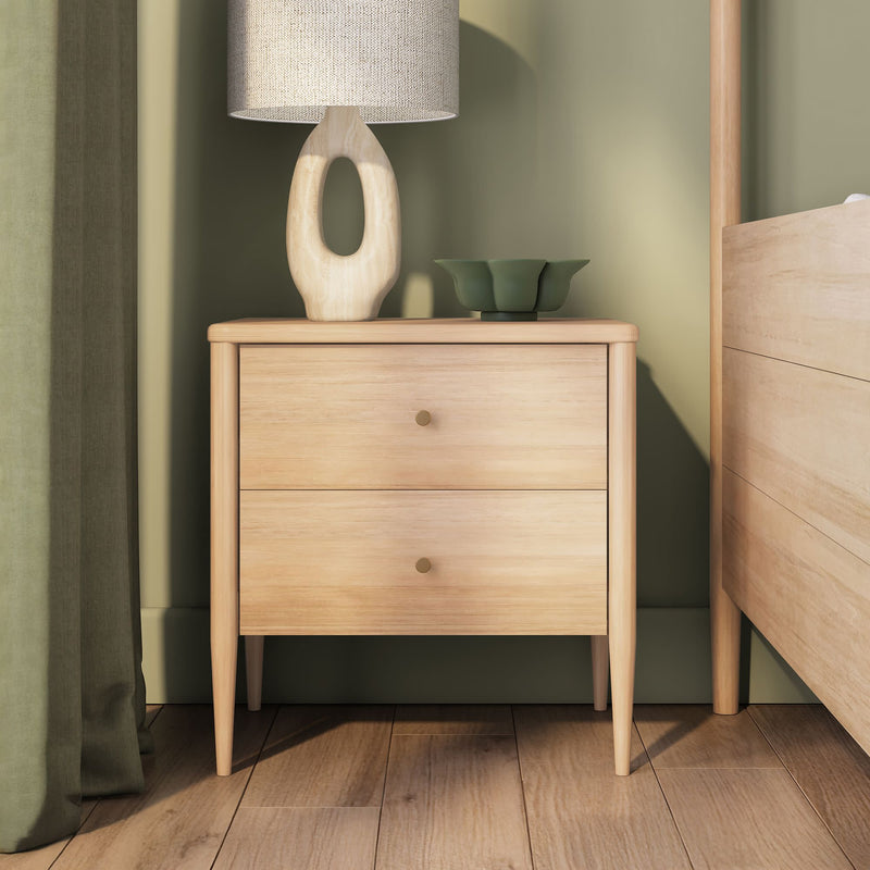 Light oak two-drawer wooden nightstand with linen lamp and green ceramic bowl against a sage-green wall — modern Scandinavian bedside table bedroom decor