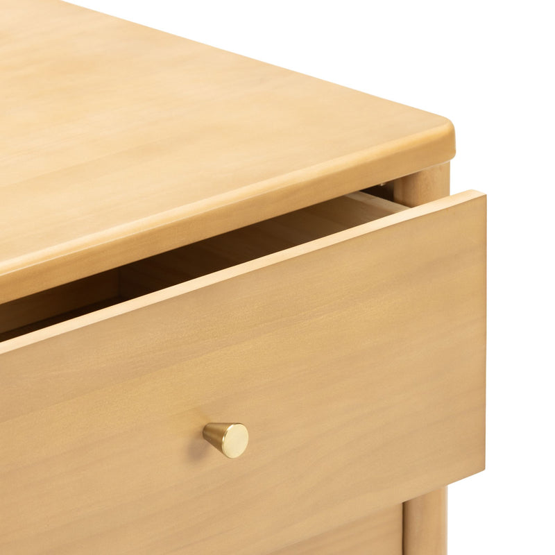 Close-up of light wood dresser drawer with round brass knob on a minimalist modern nightstand