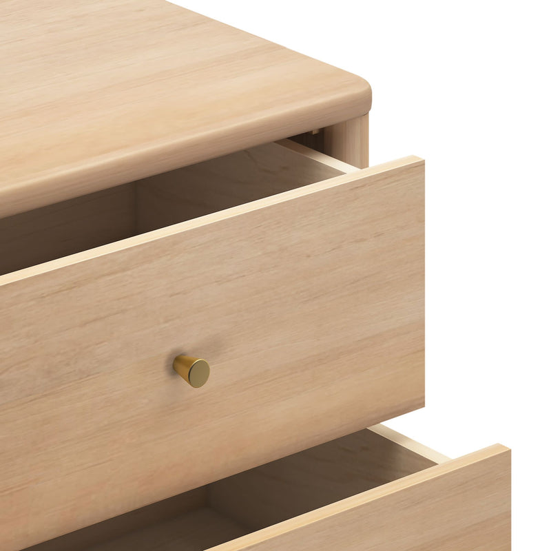 Close-up of a light natural wood dresser with two open drawers and a brass knob, minimalist modern bedroom storage chest