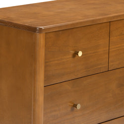 Close-up of mid-century modern solid wood dresser with warm walnut finish, rounded top edge and brass drawer knobs
