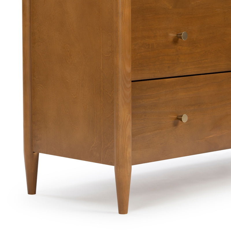 Close-up of mid-century modern wooden dresser with tapered legs, round brass knobs and warm walnut finish