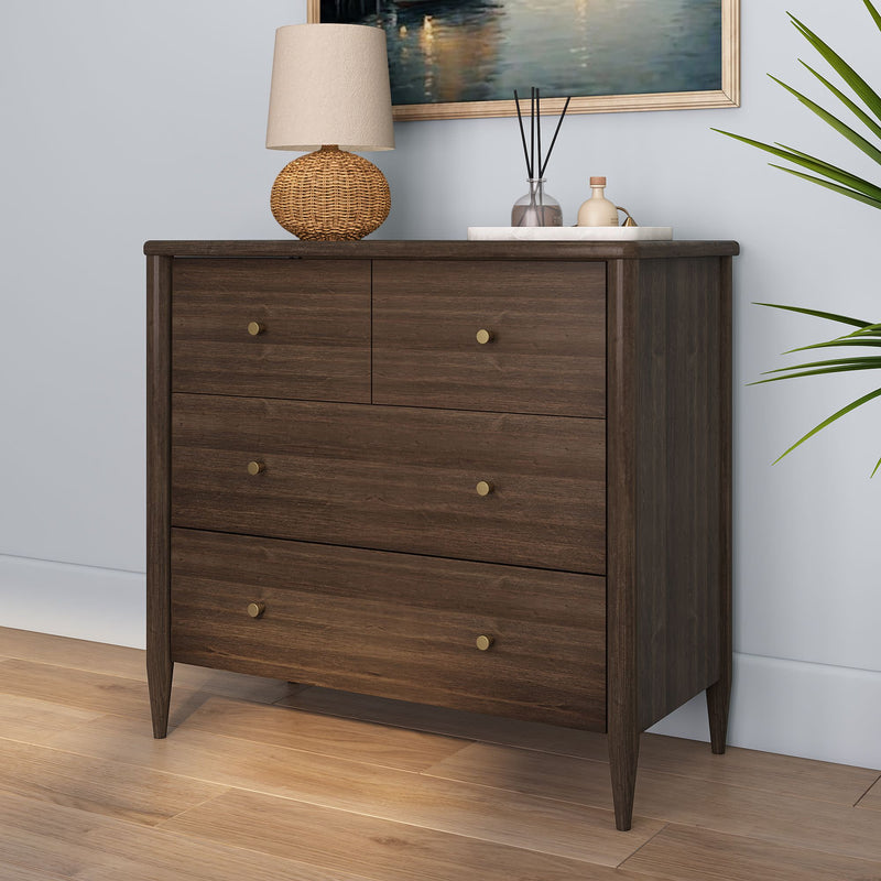 Dark walnut mid-century modern four-drawer dresser chest of drawers with brass knobs, styled on hardwood floor with rattan table lamp, reed diffuser, framed wall art and potted plant — modern bedroom storage furniture