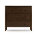 Dark walnut-finish mid-century modern chest of drawers with round brass knobs and tapered legs on white background