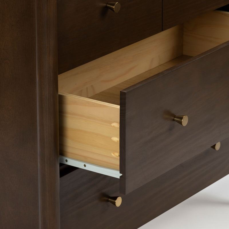 Close-up of a partially opened wooden dresser drawer with dark brown stained finish, light pine interior, visible dowel joinery, brass knobs and metal drawer slides, modern bedroom furniture detail