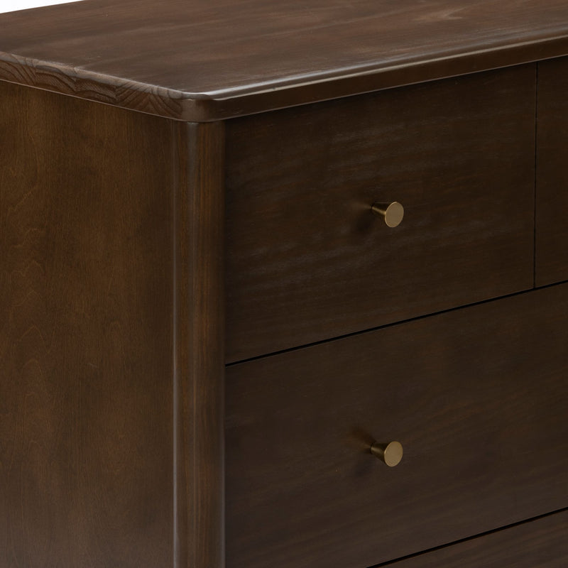 Close-up of dark brown wood dresser corner with rounded top edge and brass knob, smooth stained finish for modern bedroom furniture