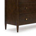 Close-up of mid-century modern dark walnut wood nightstand with tapered legs and round brass drawer knobs