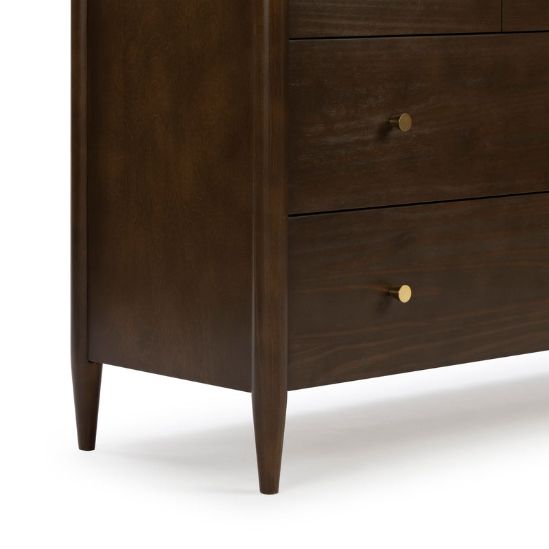 Close-up of mid-century modern dark walnut wood nightstand with tapered legs and round brass drawer knobs
