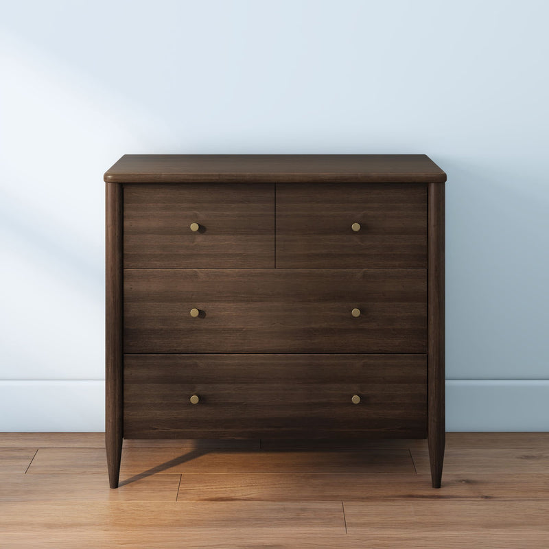 Mid-century modern dark wood four-drawer dresser with brass knobs on hardwood floor against light blue wall