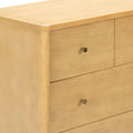 Close-up of light maple wood dresser with rounded top edge, drawers and brass cone knob — modern minimalist bedroom storage