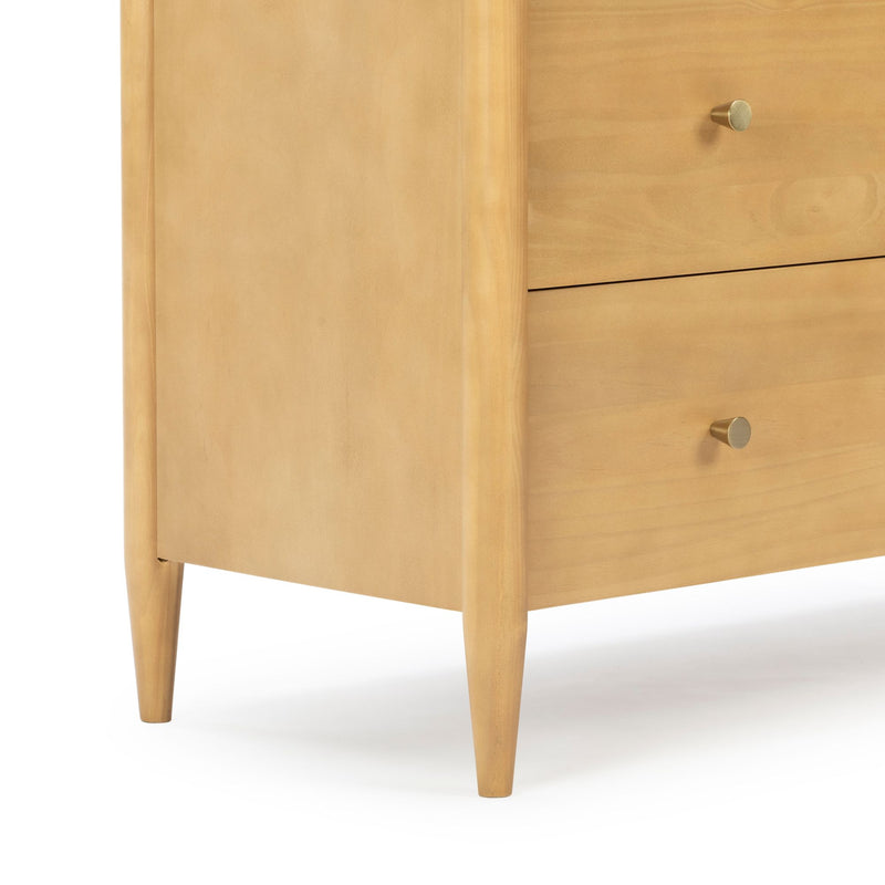 Mid-century modern light wood nightstand with tapered legs and brass knob, close-up dresser corner