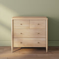 Light wood four-drawer modern dresser with brass knobs in minimalist bedroom setting against sage green wall and hardwood floor