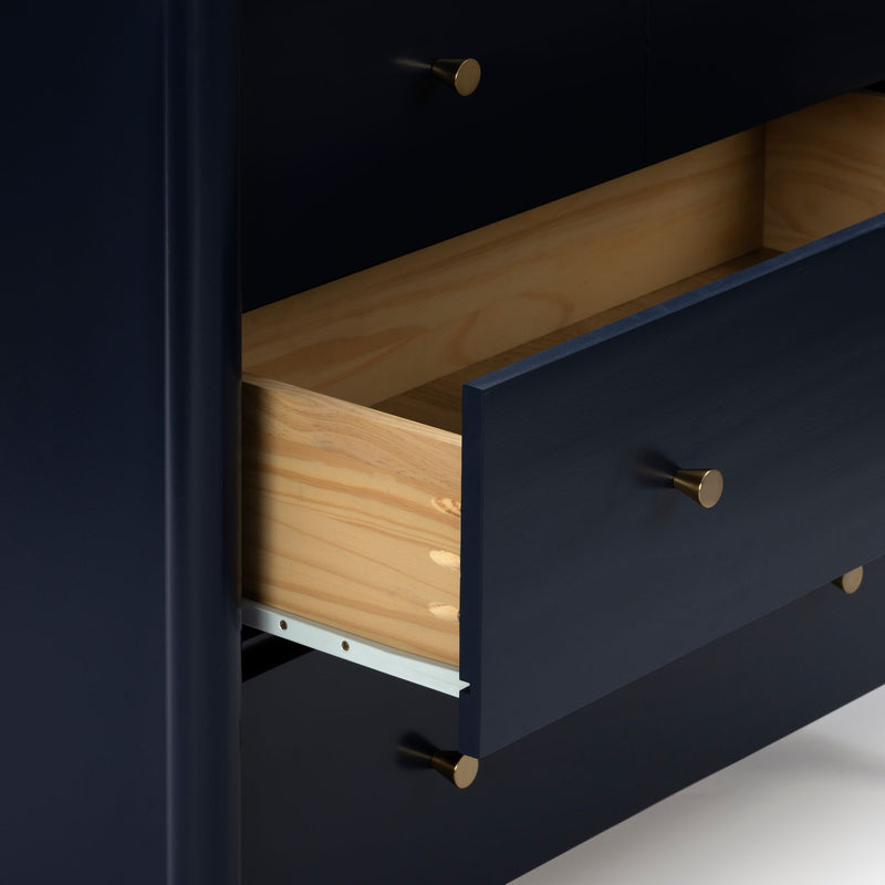 Close-up of navy blue dresser with open natural wood drawers and brass knobs — modern bedroom storage furniture