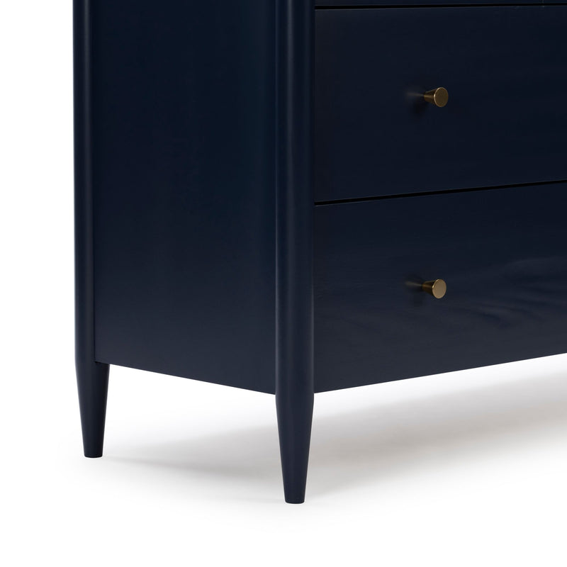 Close-up of navy blue mid-century modern dresser nightstand with brass round knob and tapered legs, smooth painted wood bedside table detail