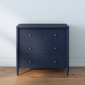 Navy blue modern chest of drawers with four drawers and brass knobs on hardwood floor against a light painted wall