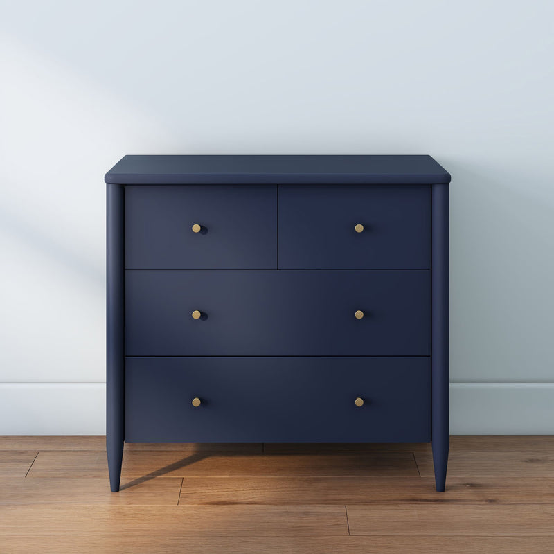 Navy blue modern chest of drawers with four drawers and brass knobs on hardwood floor against a light painted wall