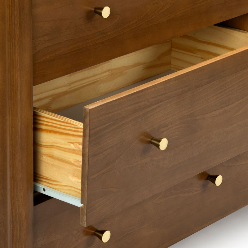 Wooden dresser drawers with one open drawer and brass knobs, close-up showing natural wood grain, light plywood interior and drawer joinery