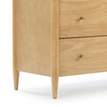 Close-up of a natural pine mid-century modern bedside nightstand with tapered legs and brass knob hardware