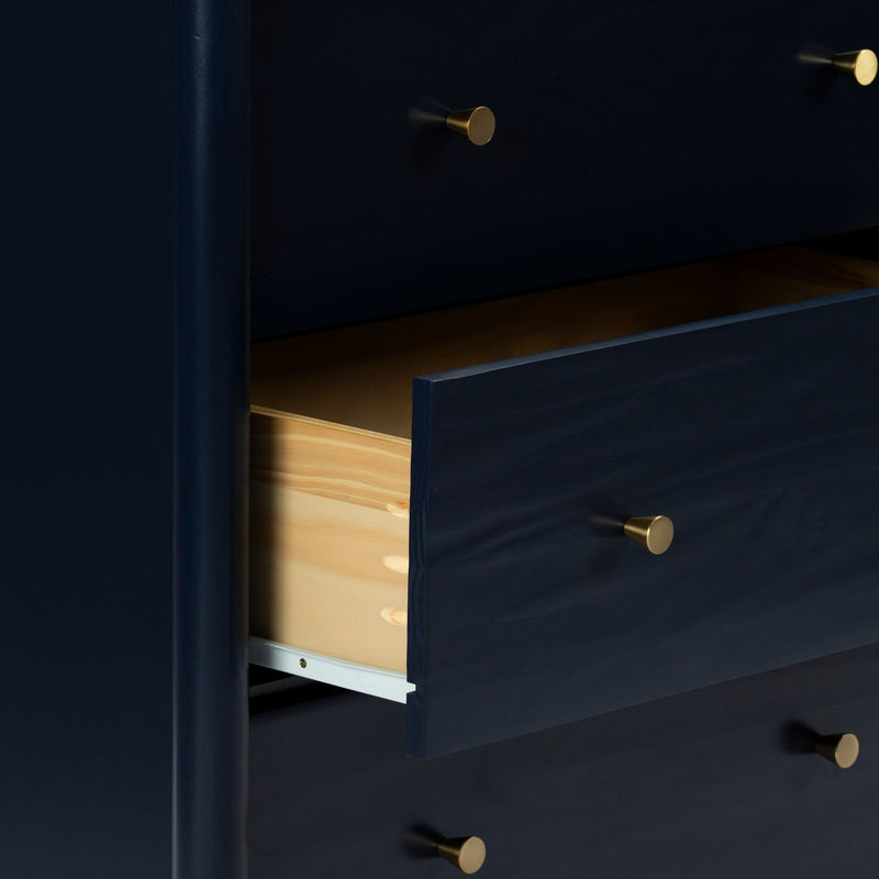 Modern navy blue wooden dresser with gold brass knobs and a partially open drawer revealing natural wood interior and finger-joint construction