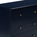 Close-up of navy blue lacquered dresser drawers with round brass knobs, modern bedroom storage cabinet