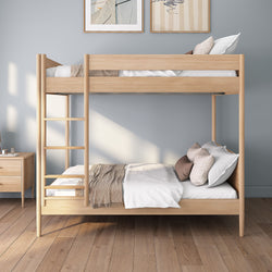 Modern natural oak wooden bunk bed with ladder in a minimalist grey bedroom, neutral bedding and pillows, hardwood floor and bedside table