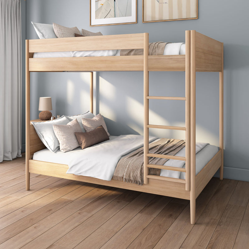 Modern light-wood twin-over-full bunk bed with ladder, neutral bedding and decorative pillows in a minimalist bedroom with hardwood floors, gray walls and bedside lamp