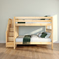 Light wooden space-saving bunk bed with staircase storage drawers and green bedding in a bright modern kids' bedroom