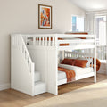White bunk bed with stairs and orange bedding in modern kids bedroom with framed cityscape art and large window city view