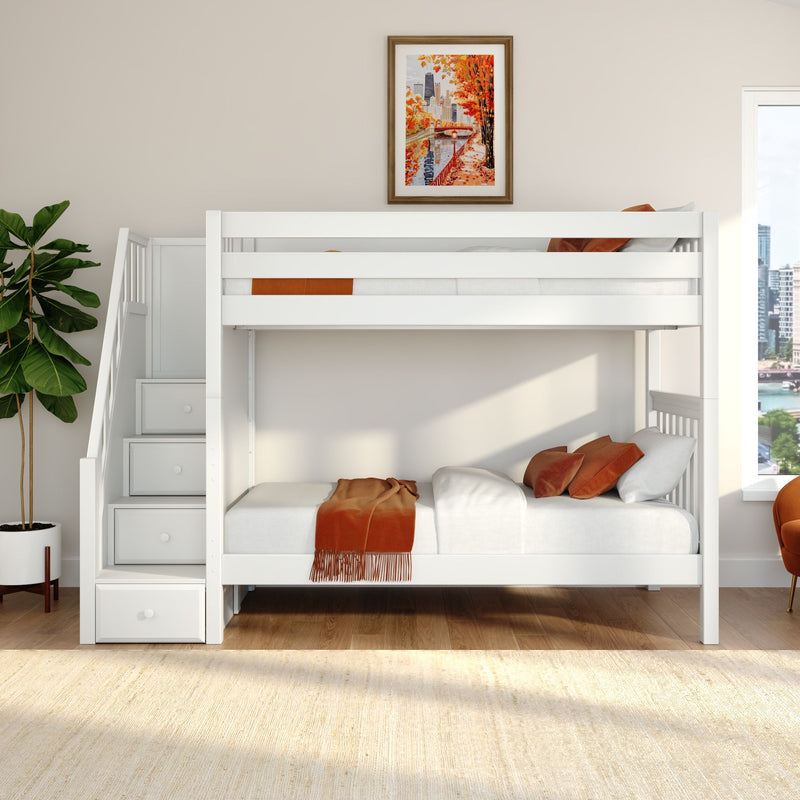 White modern bunk bed with built-in storage stairs and drawers, orange throw blanket and pillows, framed autumn cityscape print, potted fiddle leaf fig and city-view window in a bright neutral kids' bedroom