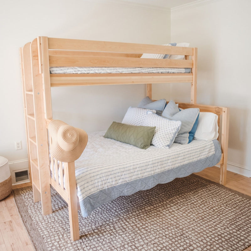 Light natural wood bunk bed in a bright neutral kids' bedroom with striped bedding, blue and green pillows, straw hat and beige textured rug