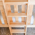 Close-up of light wood slatted furniture with natural maple finish, vertical slats and patterned rug background