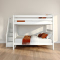 White wooden loft bunk bed with staircase storage and built-in drawers, orange throw and pillows on white bedding in a modern minimalist bedroom with hardwood floors and beige wall
