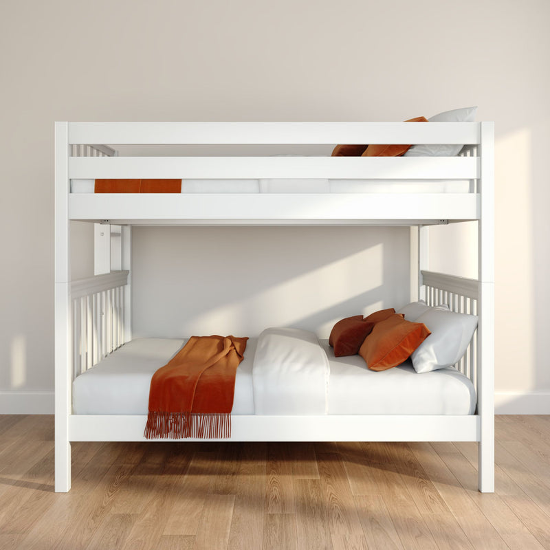 White wooden bunk bed in a minimalist bedroom with white bedding, orange throw pillows and blanket, natural light and hardwood floor