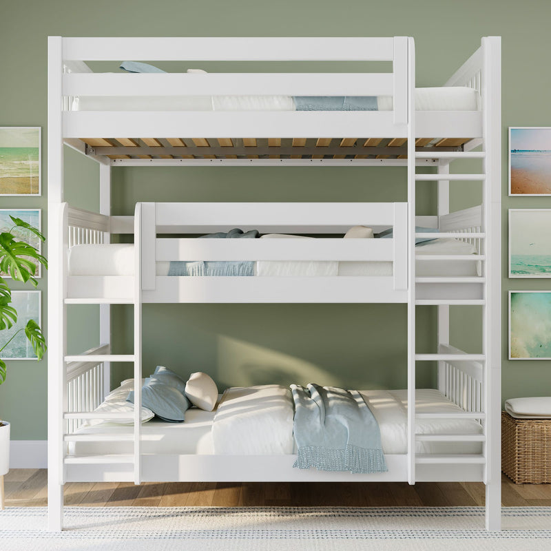 White wooden triple bunk bed with ladders and light blue bedding in bright kids' bedroom with green accent wall, coastal wall art, and hardwood floor