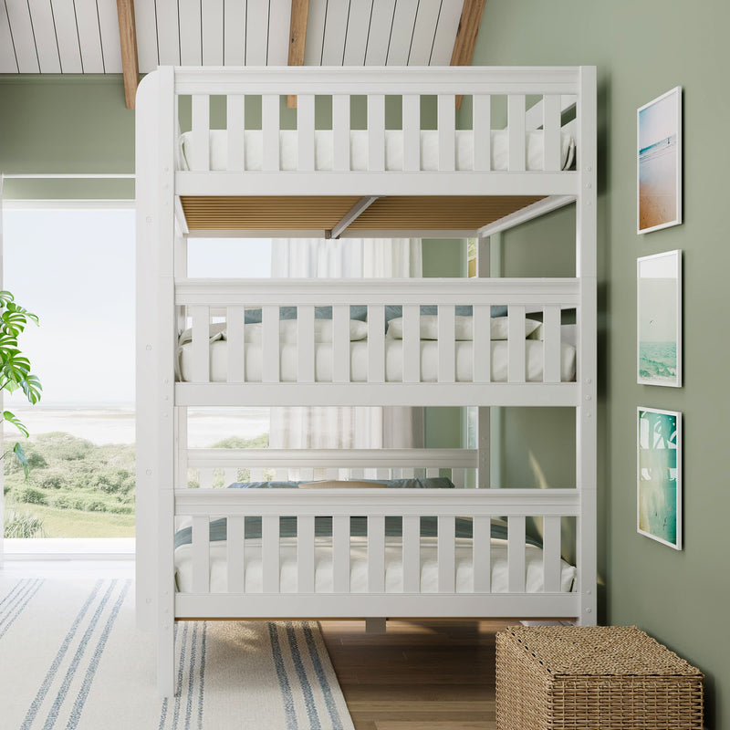 White wooden triple bunk bed in coastal kids bedroom with green walls, beach view, framed art and wicker storage