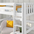 White loft bed with ladder, blue leaf-pattern bedding, mustard yellow pillow on gray armchair, and potted plant in kids' room