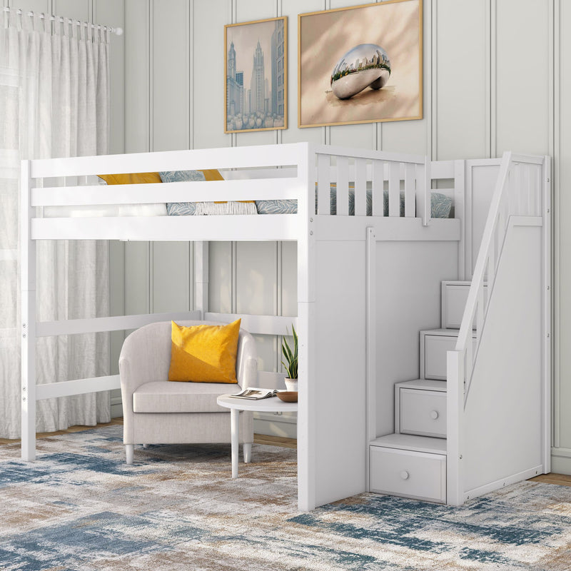 White wooden loft bed with staircase drawers and built-in storage over a cozy reading nook with a beige armchair and yellow accent pillow, round white side table, potted plant, blue-beige patterned rug and framed city artwork in a modern kids' bedroom