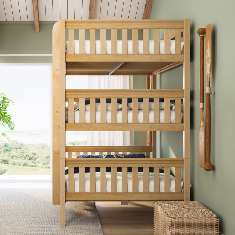Natural wood triple bunk bed in coastal kids' bedroom with green walls, large window beach view, decorative oars and wicker storage.
